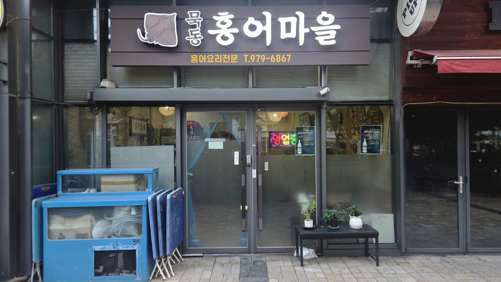 묵동홍어마을 간판과 출입구 정면. 출입구 왼편에 파란 보관함이 있다